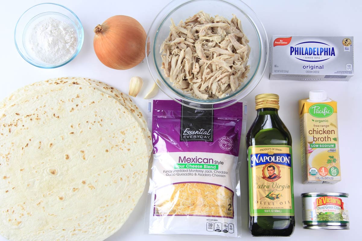 Ingredients for Easy Chicken Enchiladas including tortillas, shredded chicken and cheese, olive oil, chicken broth, chiles, cream cheese, onion, garlic, and flour. 