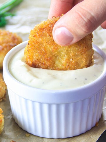 Vertical image of a Healthy Chicken Nugget in Quinoa being dipping into a sauce
