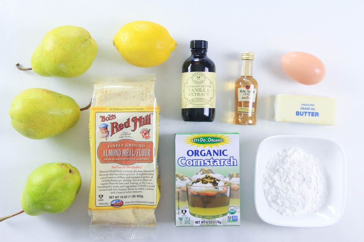 Ingredients for Pear Tart filling and pears, including almond flour, cornstarch, lemon, vanilla, rum, egg, butter, sugar, and pears