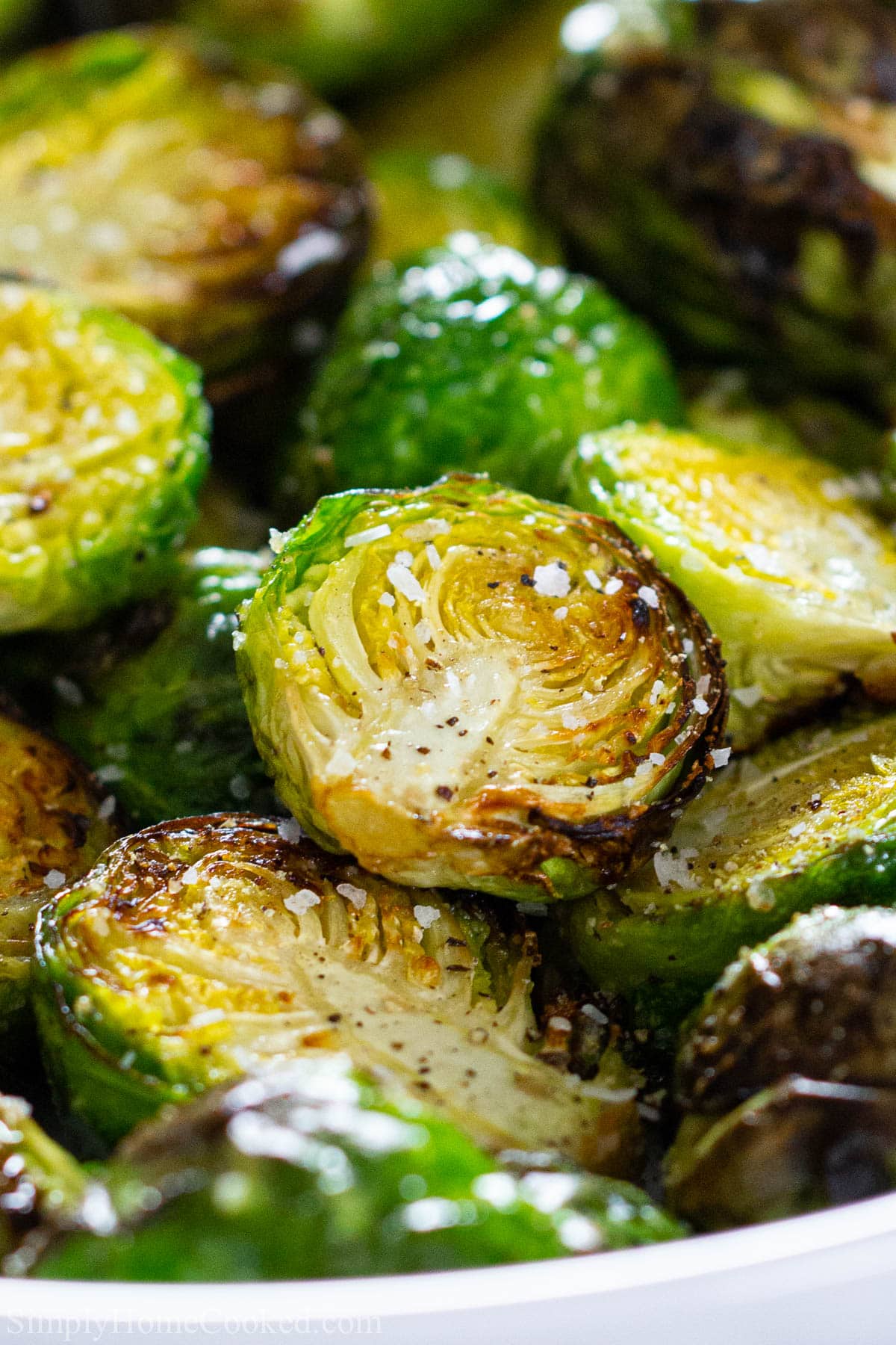 These Crispy Air Fryer Brussels Sprouts are a quick and easy vegetable that you can make in minutes. They also taste delicious and go great with most meals. #crispybrusselsprouts #yummylittlecabbages #brusselssprouts #airfryerbrusselssprouts Vertical image of Air Fryer Brussels Sprouts