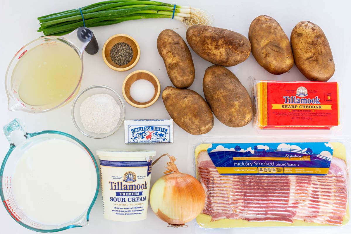 Easy Potato Soup with Bacon is a delicious and warming meal for any cold day. This easy recipe in under one hour making it a perfect weeknight meal. #potatosoup #creamysoup #comfortsoup #wintersoup #easysoup Ingredients for Baked Potato Soup, including potatoes, bacon, flour, broth, milk, sour cream, cheese, butter, onion, green onion, salt, and pepper.