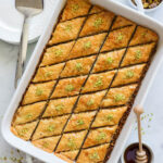 Baking dish of Baklava, slices and garnished with ground pistachios.
