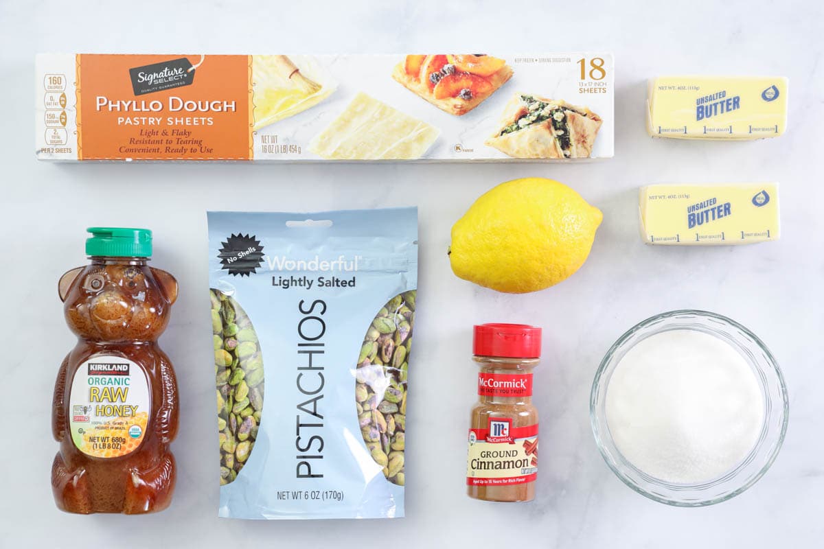Ingredients for Baklava recipe, including  phyllo dough, honey, pistachios, lemon, sugar, cinnamon, and butter.