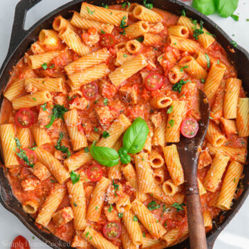 Pan of Chicken Riggies with a wooden spoon in it and basil on top.