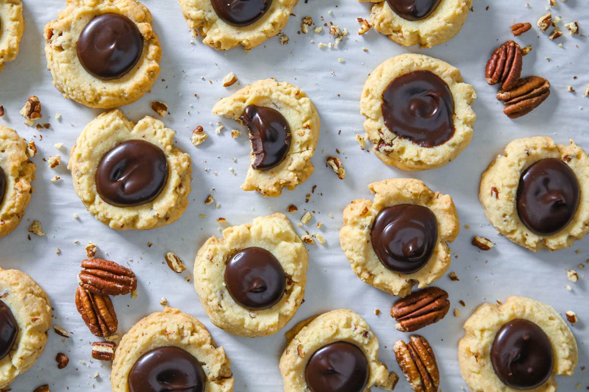 Chocolate Thumbprint Cookies on parchment paper with pecans scattered around.