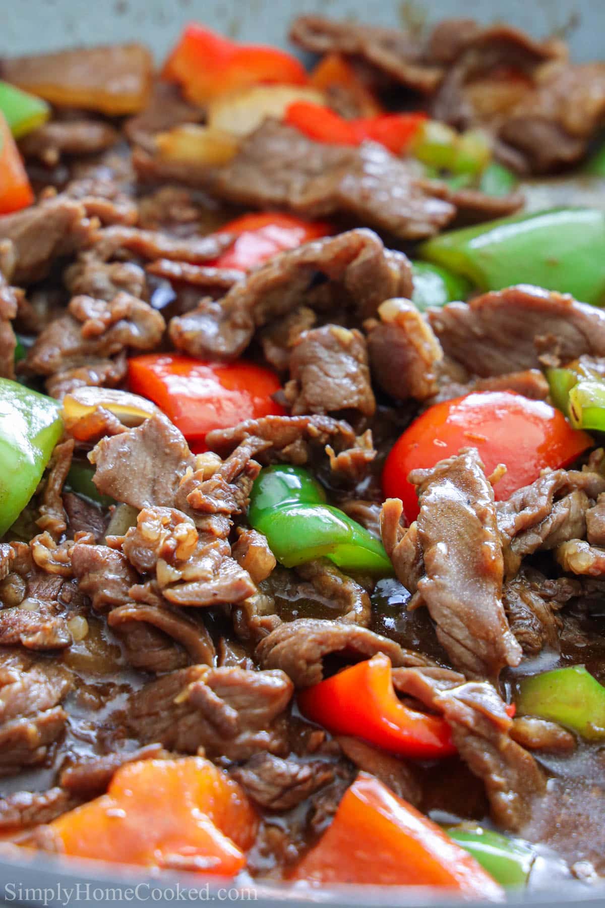 This Pepper Steak recipe will surely become a family favorite. Savory marinated meat and crisp vegetables, plus a garlicky sauce make this dish absolutely delicious. #Peppersteak #peppersteakrecipe #weeknightmeal #easypeppersteak close up image of pepper steak with sauce over the top