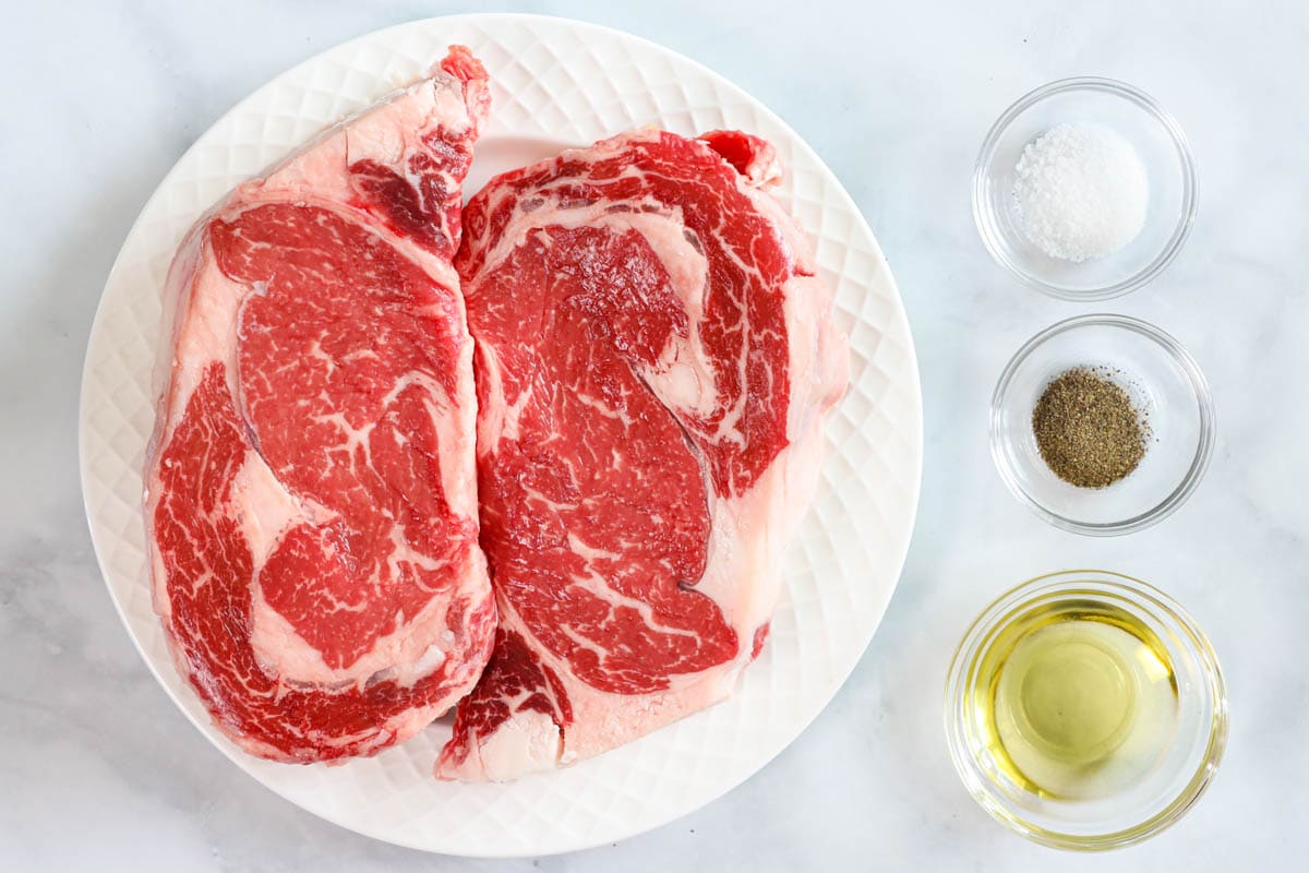 Ingredients for Juicy Air Fryer Steak including ribeye steaks, avocado oil, salt, and pepper.