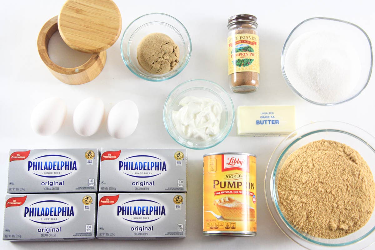 Ingredients for Pumpkin Cheesecake, including graham crackers, brown sugar, butter, pumpkin puree, pumpkin pie spice, cream cheese, sugar, salt, eggs, and sour cream.