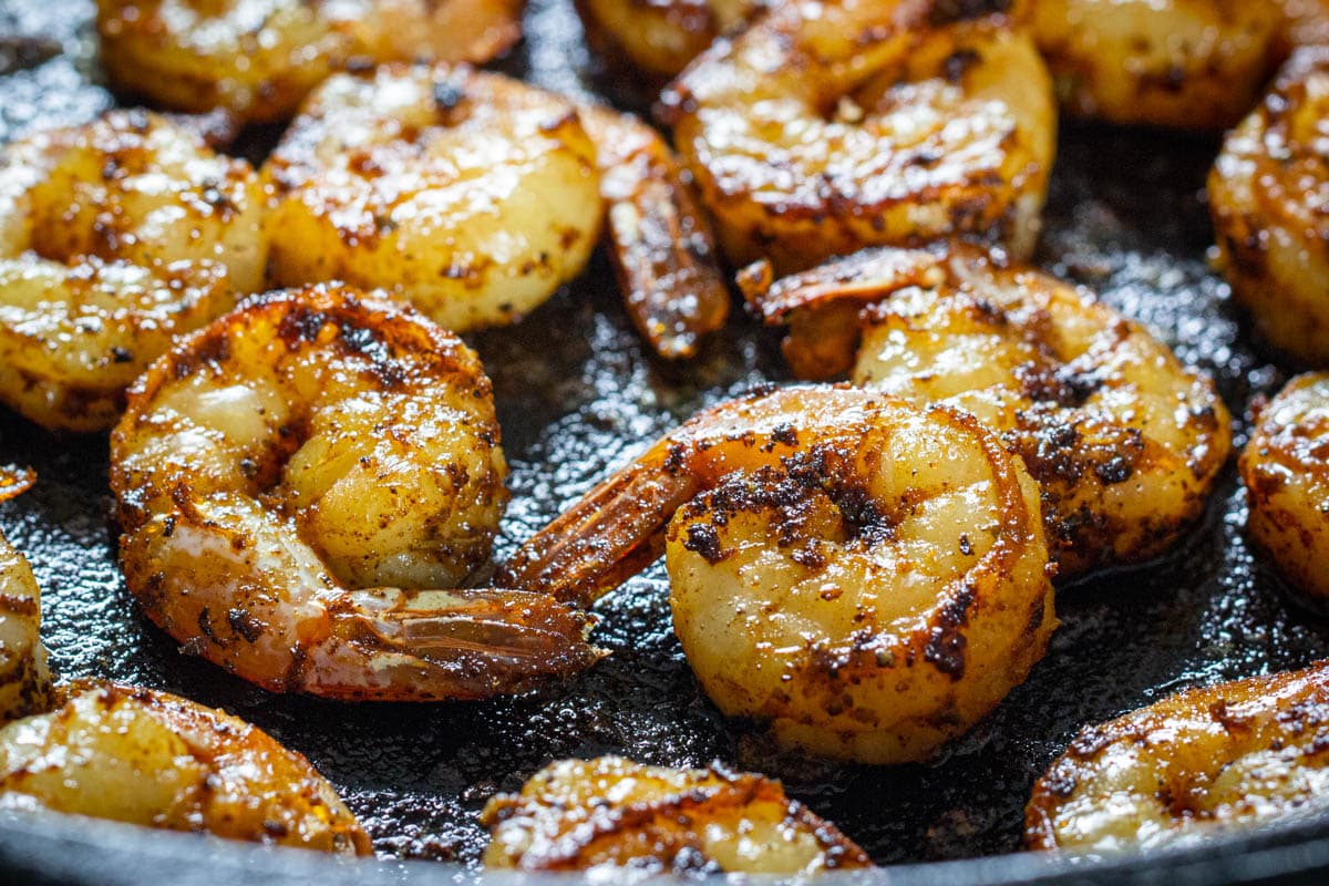 Blackened cajun shrimp are flavorful, not too spicy, and easy to make. You can prepare them in 10 minutes and they really enhance a salad, pasta, or rice dish. #cajunshrimprecipe #easyblackenedshrimpmeal #10minutemeal #easyshrimpdinnerideas Horizontal image of Cajun Shrimp in a skillet