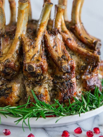 Vertical image of Pork Crown Roast surrounded by rosemary and pomegranate seeds.