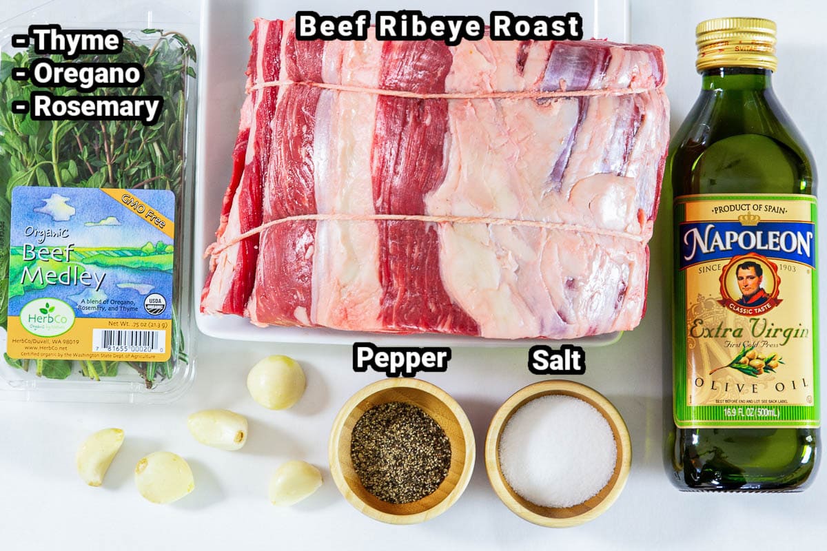 Prime rib roast is a flavorful dish to serve at any party or gathering. Easy to make, this roast has a delicious outer herb crust and a juicy center. #primerib #homemaderibroast #deliciousrprimerib #ribroastdinner #primeribroast Ingredients for Prime Rib, including beef ribeye roast, olive oil, thyme, oregano, rosemary, salt, pepper, and garlic cloves.