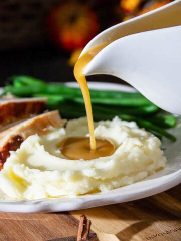 Vertical image of Turkey Gravy being drizzled on to mashed potatoes