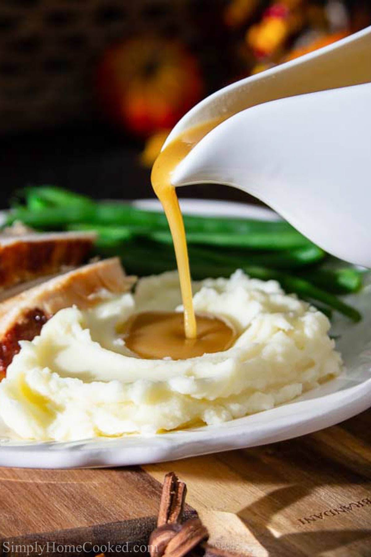 This 4 ingredient turkey gravy is full of rich flavor from the turkey drippings. You won't believe how something so simple can taste so insanely delicious! #turkeygravy #gravyrecipe #thanksgivinggravy #easygravy #thanksgivingfood Vertical image of Turkey Gravy being drizzled on to mashed potatoes