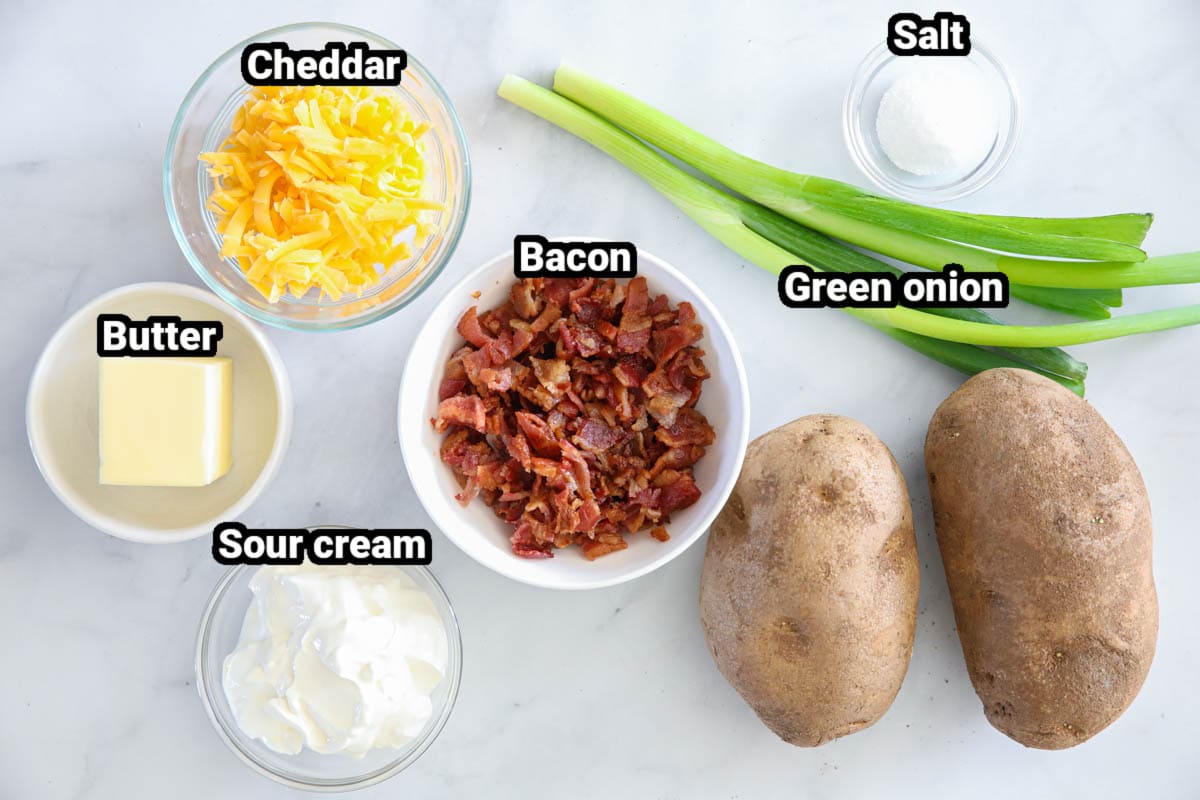 Ingredients for Air Fryer Baked Potato, including russet potatoes, green onions, salt, butter, sour cream, bacon, and cheddar cheese.