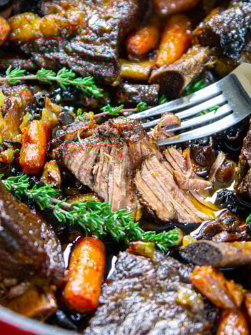 Vertical close up image of Braised Beef Short Ribs on a fork