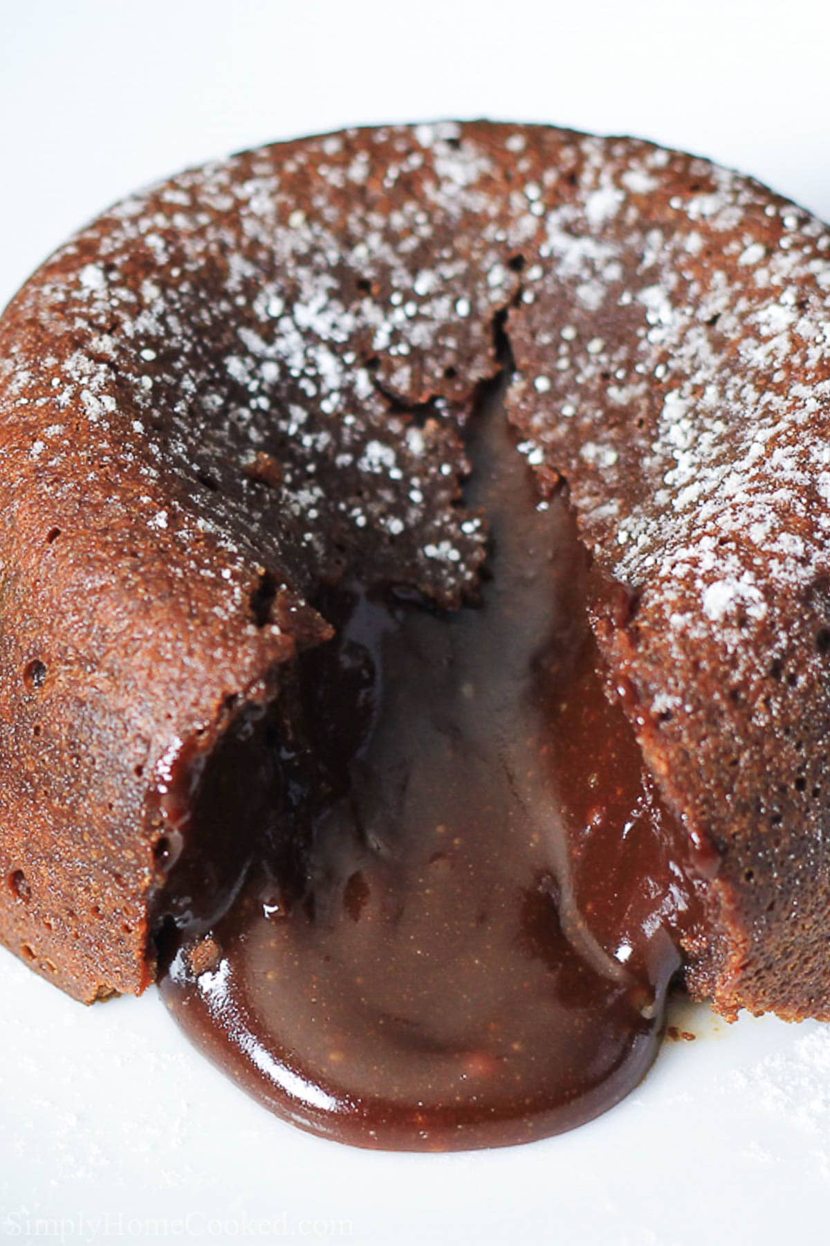 Vertical close up image of a split open Chocolate Lava Cake with powdered sugar on top