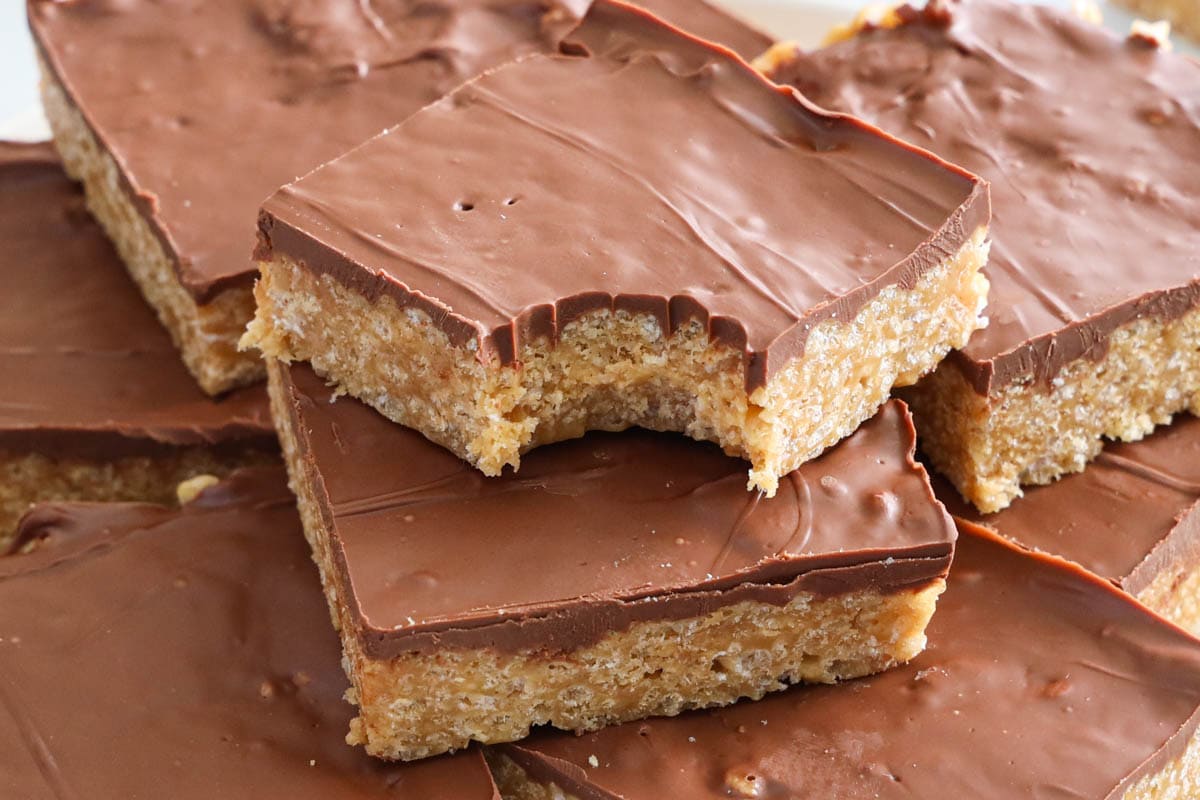 Horizontal image of Scotcheroos piled up on top of each other, the top one missing a bite