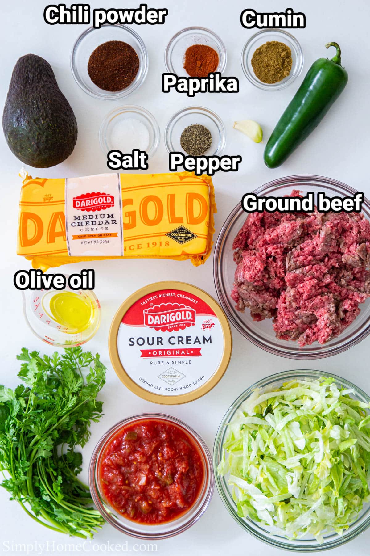 Ingredients for Taco Salad Recipe, including Ground beef, chili powder, cumin, paprika, salt, pepper, jalapeno, avocado, cheese, oil, cilantro, tomatoes, shredded lettuce, and sour cream.