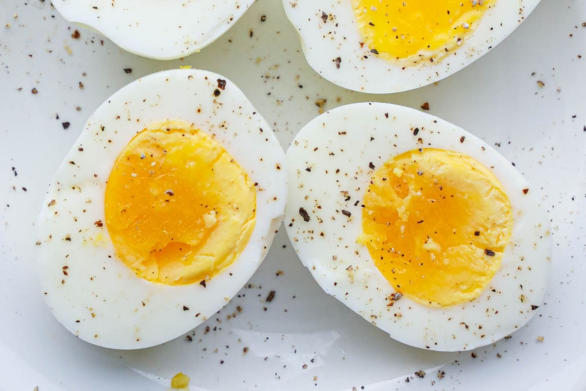 Horizontal image of Air Fryer Hard Boiled Eggs peeled and cut, topped with salt and pepper.