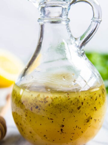 Vertical image of Greek Salad Dressing in a glass dressing bottle