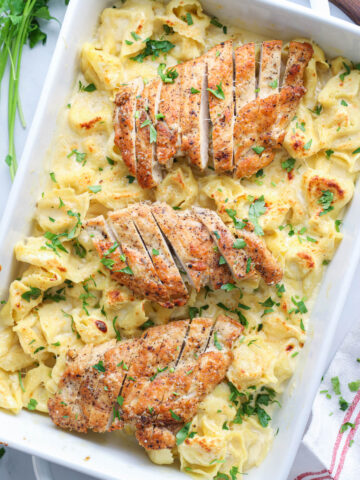 Asiago Tortelloni Alfredo with Grilled Chicken in a baking dish with parsley sprinkled on top