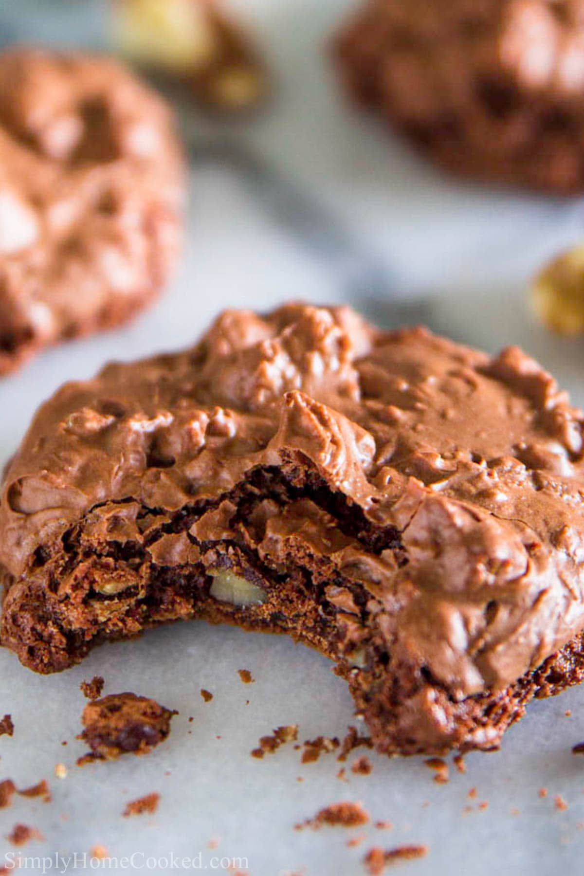 These chocolate meringue cookies are beyond irresistible (they are flourless)! They're loaded with walnuts and have a crispy exterior with a chewy chocolatey center. #meringue #meringuecookies #glutenfreecookies Closeup of a Chocolate Meringue Cookie missing a bite
