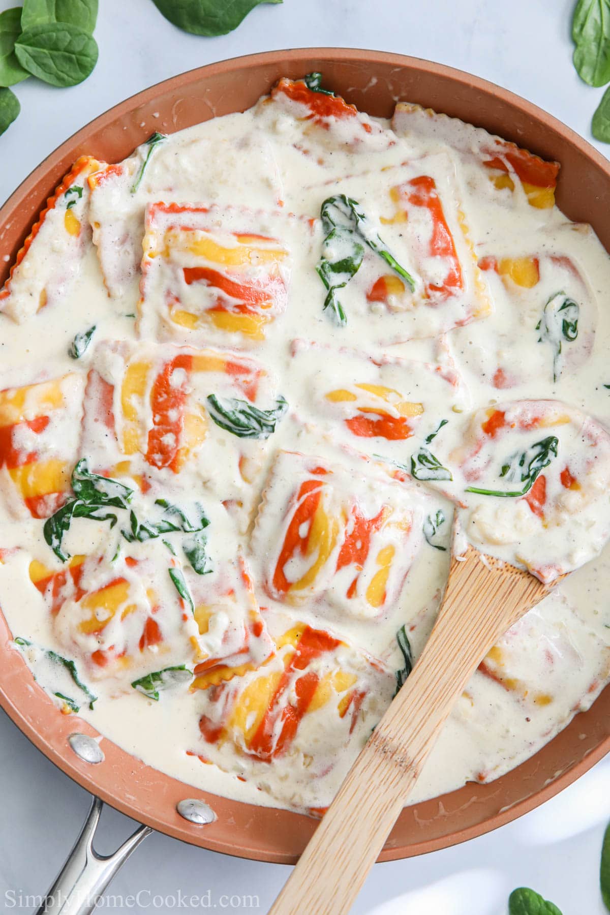 Lobster Ravioli in a skillet with a wooden spoon stirring it.