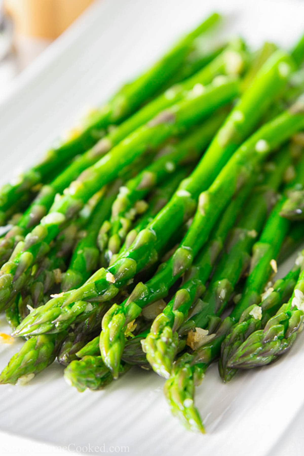 Quick, easy, and healthy sautéed garlic asparagus. A simple and delicious side to almost any meal. #healthysides #garlicasparagus #asparagus #vegetablesides #paleosides #whole30sides #ketosides Sauteed Garlic Asparagus on a white plate