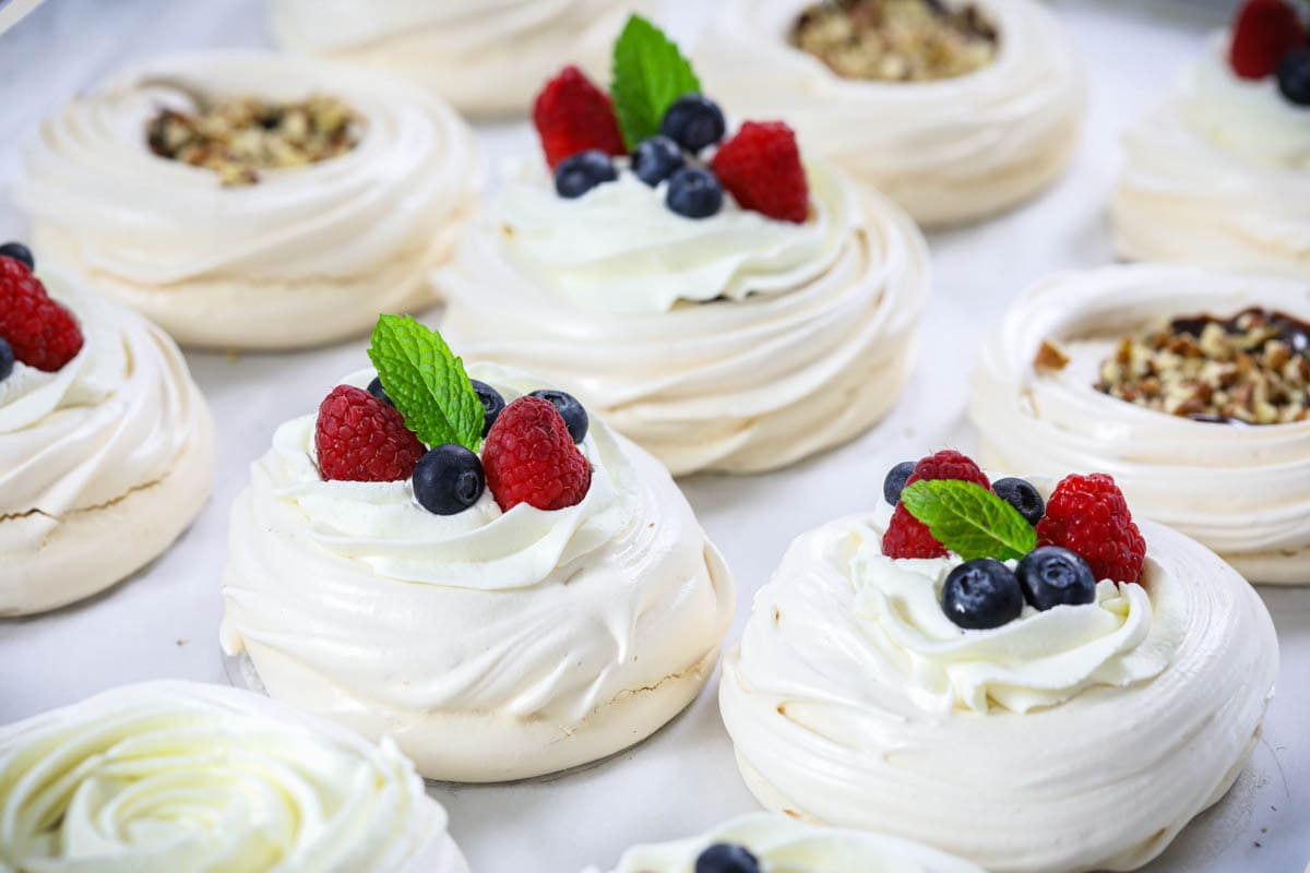 Mini Pavlova with Chocolate and pecans and some topped with whipped cream and berries