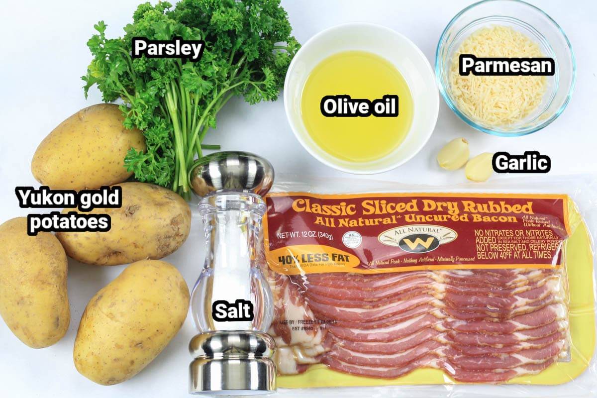 Ingredients for Parmesan Roasted Potatoes, including Yukon gold potatoes, parsley, parmesan, olive oil, garlic, salt, and bacon.
