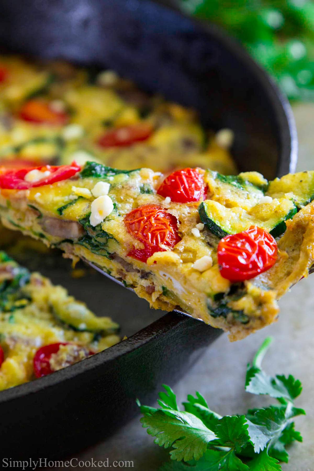 Close up of a slice of Zucchini Frittata being lifted from a cast iron skillet.