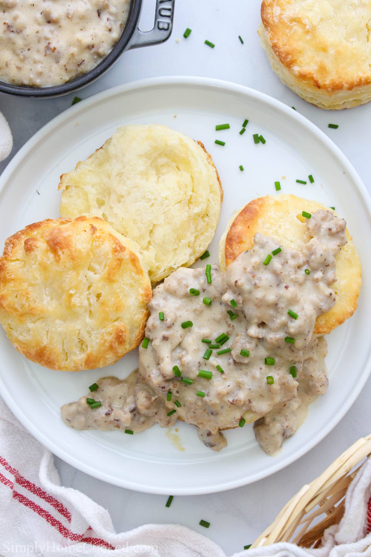 This Best Sausage Gravy is savory, buttery, and creamy. It goes perfectly with your favorite biscuits, waffles, and fried chicken - and only takes 15 min! #quicksausagegravy #bestsausagegravy #bestsausagegravyrecipe #sausagegravyrecipe Plate of Biscuits and Sausage Gravy topped with chives