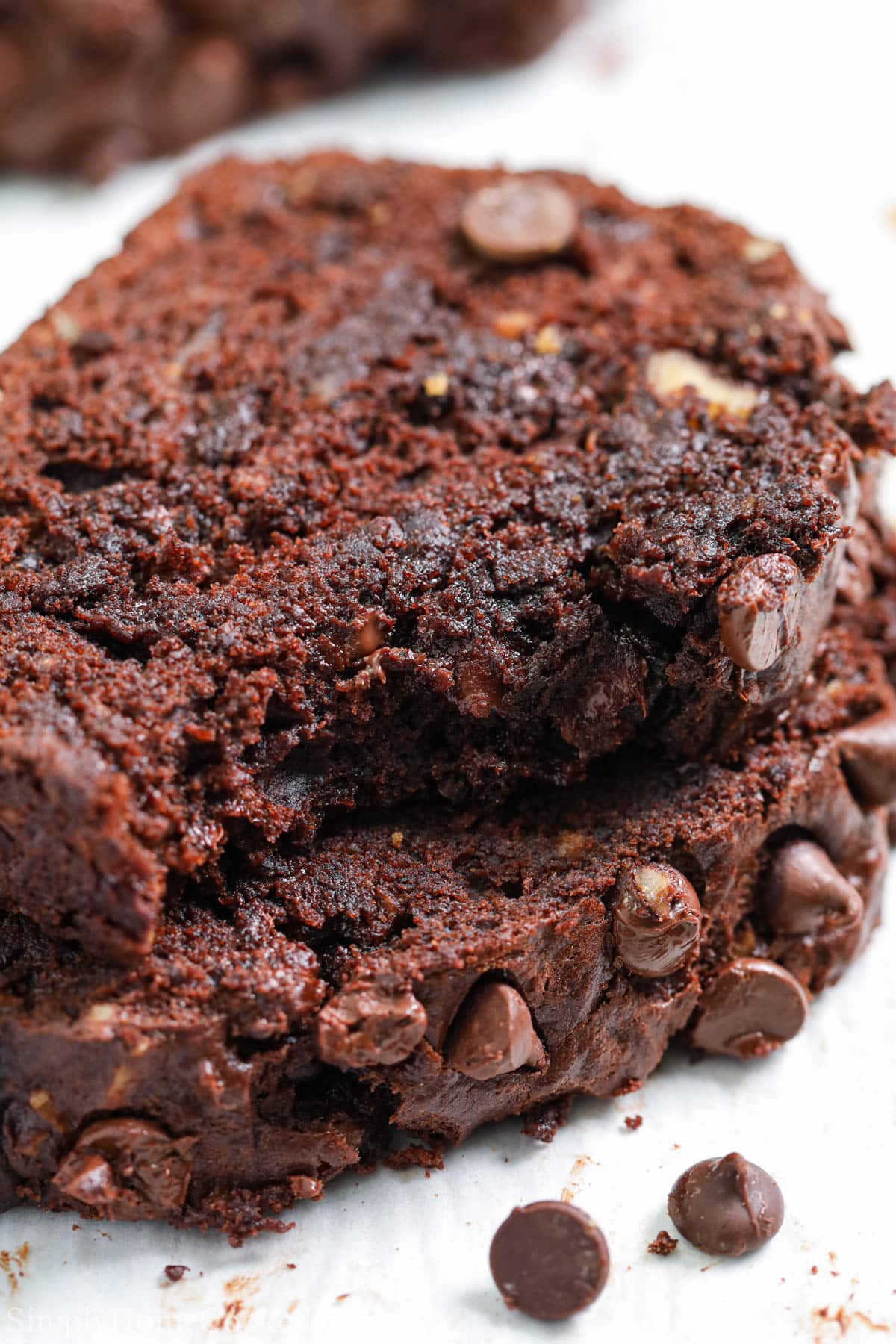 This Double Chocolate Banana Bread recipe is so rich & moist! Chocolate chips, toasted walnuts & ripe bananas give it the perfect taste & texture. #doublechocolatebananabread #doublechocolatebananabreadrecipe #bananawalnutbreadrecipe #chocolatewalnutbananabread Slices of Double Chocolate Banana Bread, one missing a bite