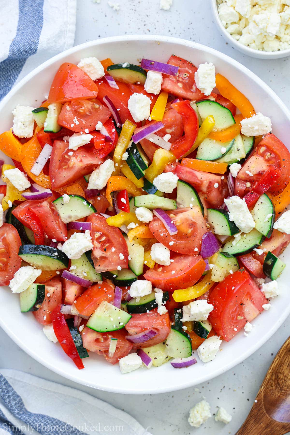 Crunchy cucumbers and crisp bell peppers make this cucumber tomato feta salad a delicious side this for just about any meal. #cucumbersalad #greeksalad #tomatosalad #crunchysalad Cucumber Tomato Feta Salad on a plate