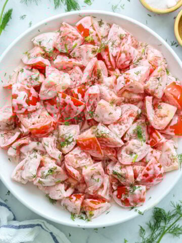 Plate of Tomato Garlic Salad topped with fresh dill.