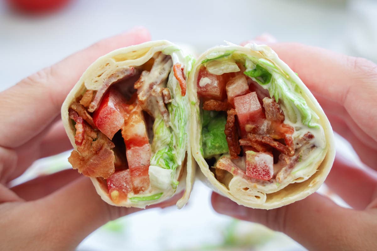 Hands holding two halves of an Easy BLT Wrap