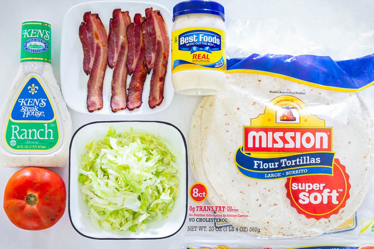 Ingredients for an Easy BLT Wrap: flour tortillas, ranch, mayo, bacon, lettuce, and tomato.