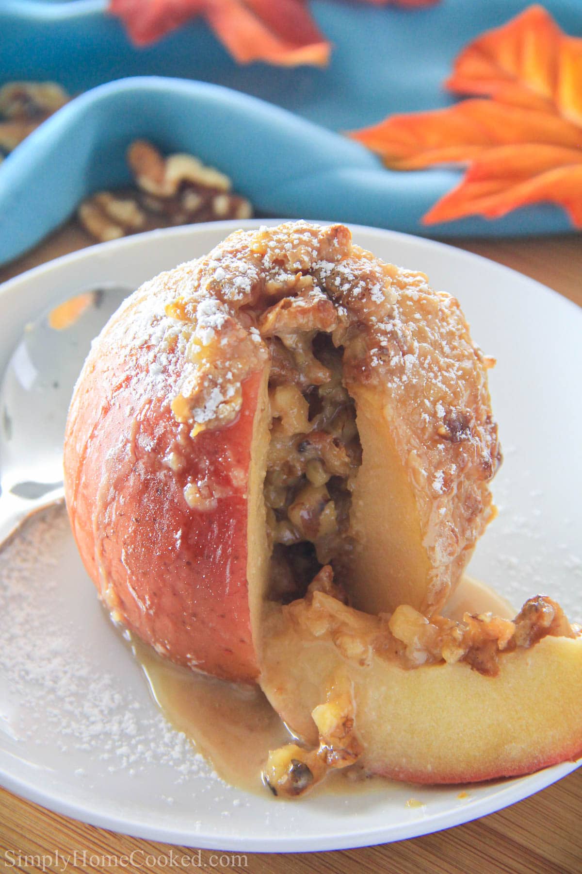 These are the best Baked Apples! and they are so easy to make. They are stuffed with walnuts and dulce de leche. The perfect fall dessert. #bakedapples #falldessert #bakedapple #appledessert Baked Apple with a slice cut out on a white plate
