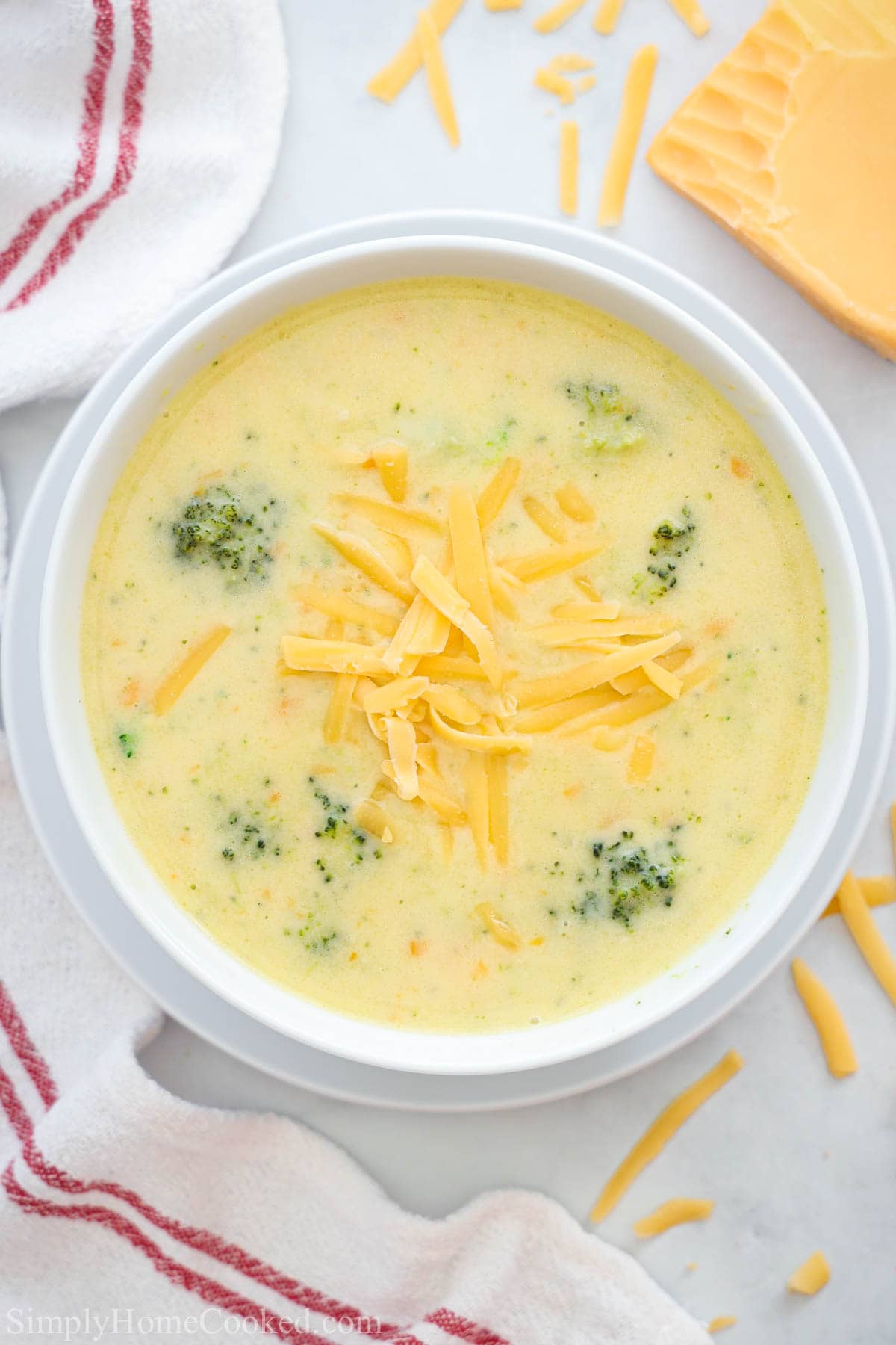 This Copycat Panera Bread Broccoli Cheddar Soup Recipe is full of vegetables in a delicious cheesy cream soup base that will satisfy everyone. #cheddarsoup broccolicheddarsoup #paneracopycatsoup #broccolicheesesoup Overhead view of a bowl of Broccoli Cheddar Soup with shredded cheese on top.