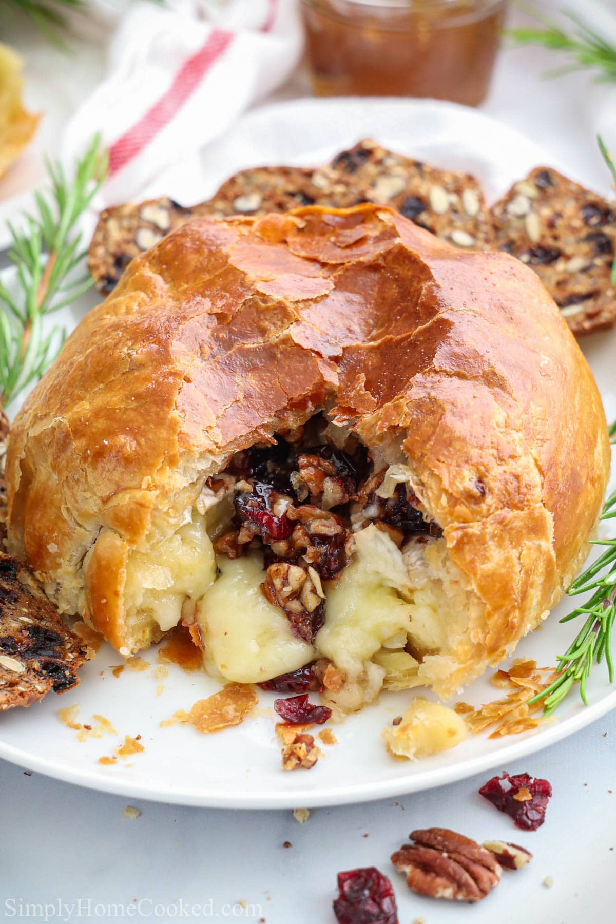 Baked Brie in Puff Pastry with brie, pecans, and cranberries spilling out.