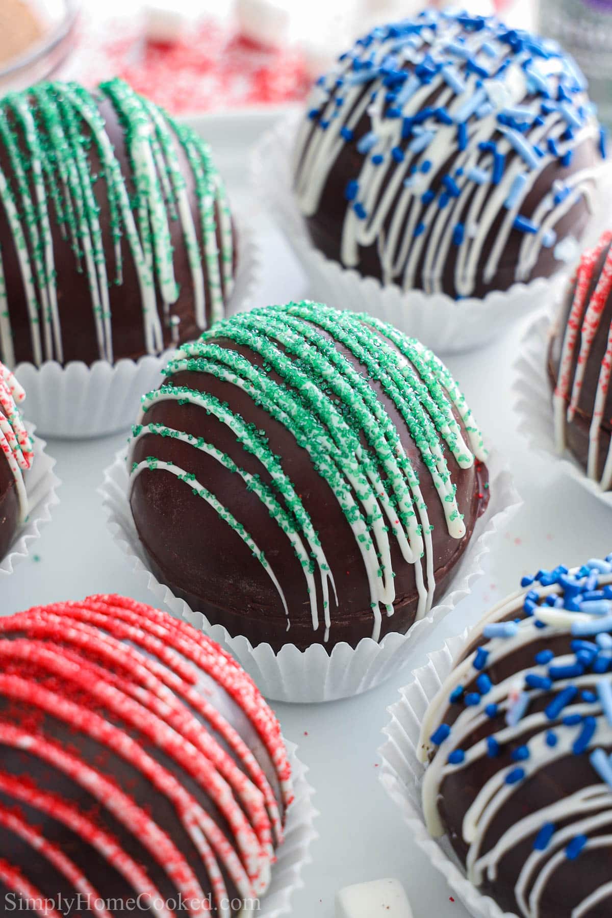 Hot Chocolate Bombs coovered in white chocolate drizzles and sprinkles.