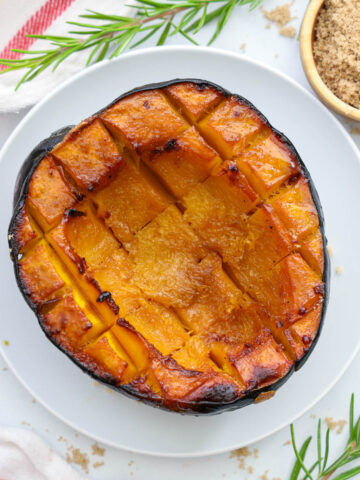 Half a Roasted Acorn Squash on a white plate.