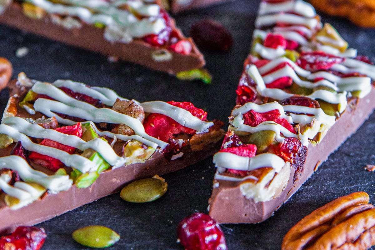 Fine quality chocolate, toasted nuts, and dried fruit make the perfect holiday chocolate bark. It's an easy no-bake dessert perfect for holiday potlucks. #chocolatebark #nobake #chocolatedessert #nobakedessert #quickdessert #easydessert Pieces of Chocolate Bark