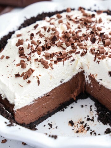 Chocolate Cream Pie with custard, whipped cream, and chocolate shavings in a pie plate, one slice missing.