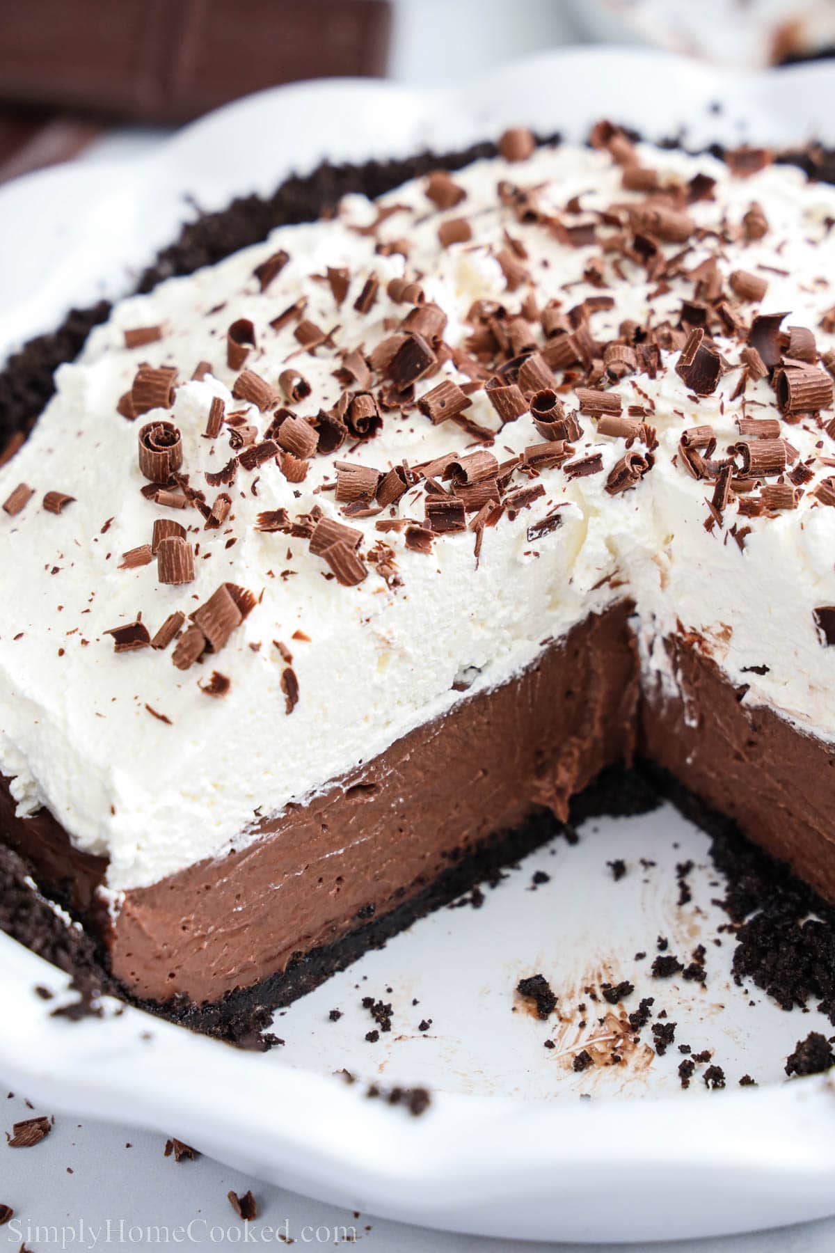 Chocolate Cream Pie with custard, whipped cream, and chocolate shavings in a pie plate, one slice missing.
