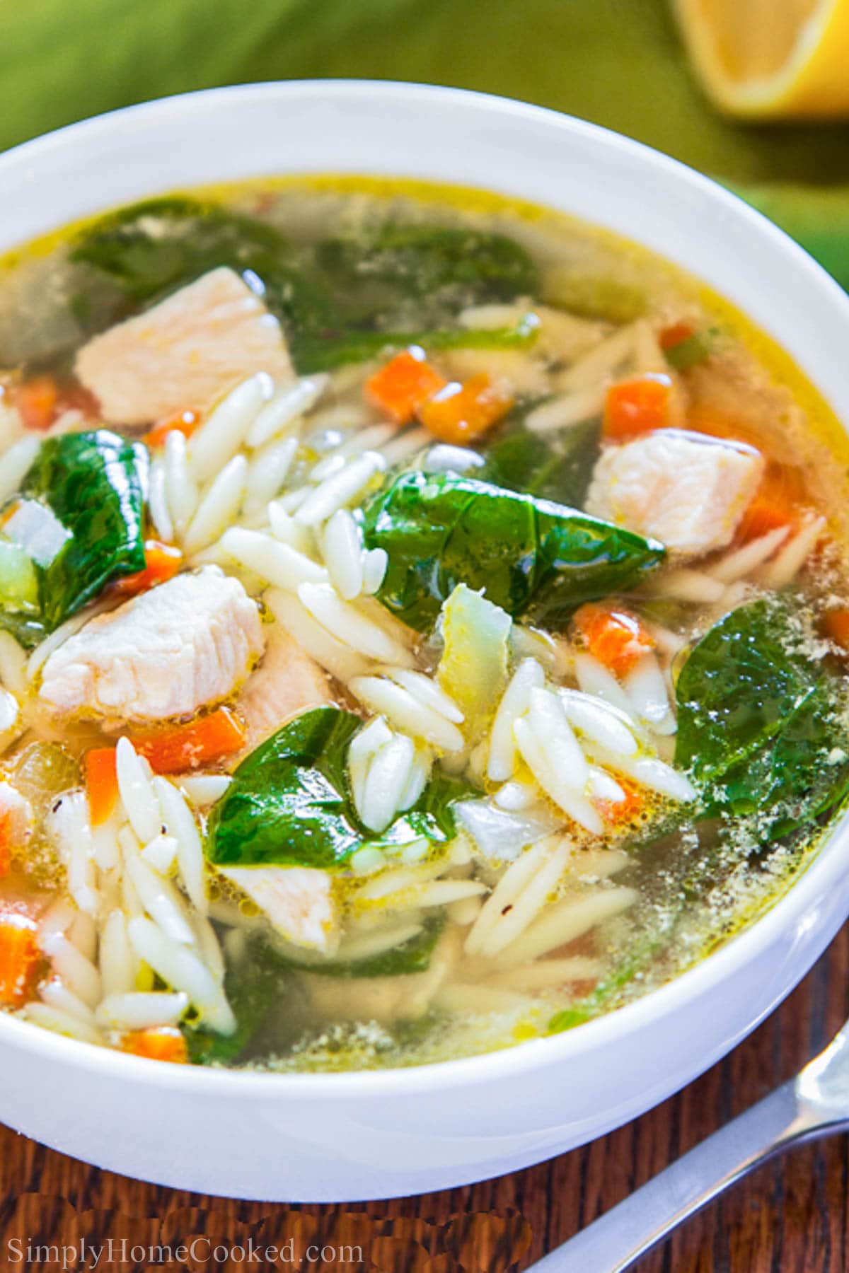 This Lemon chicken orzo soup recipe is so brothy, comforting, and bursting with lemony flavor. The tiny bits of chicken and orzo are so tender and delicious #lemonchicken #chickenorzosoup #orzosoup #lemonchickensoup #chickennoodlesoup #healthysoup Bowl of Lemon Chicken Orzo Soup with orzo, spinach, chicken, and broth.