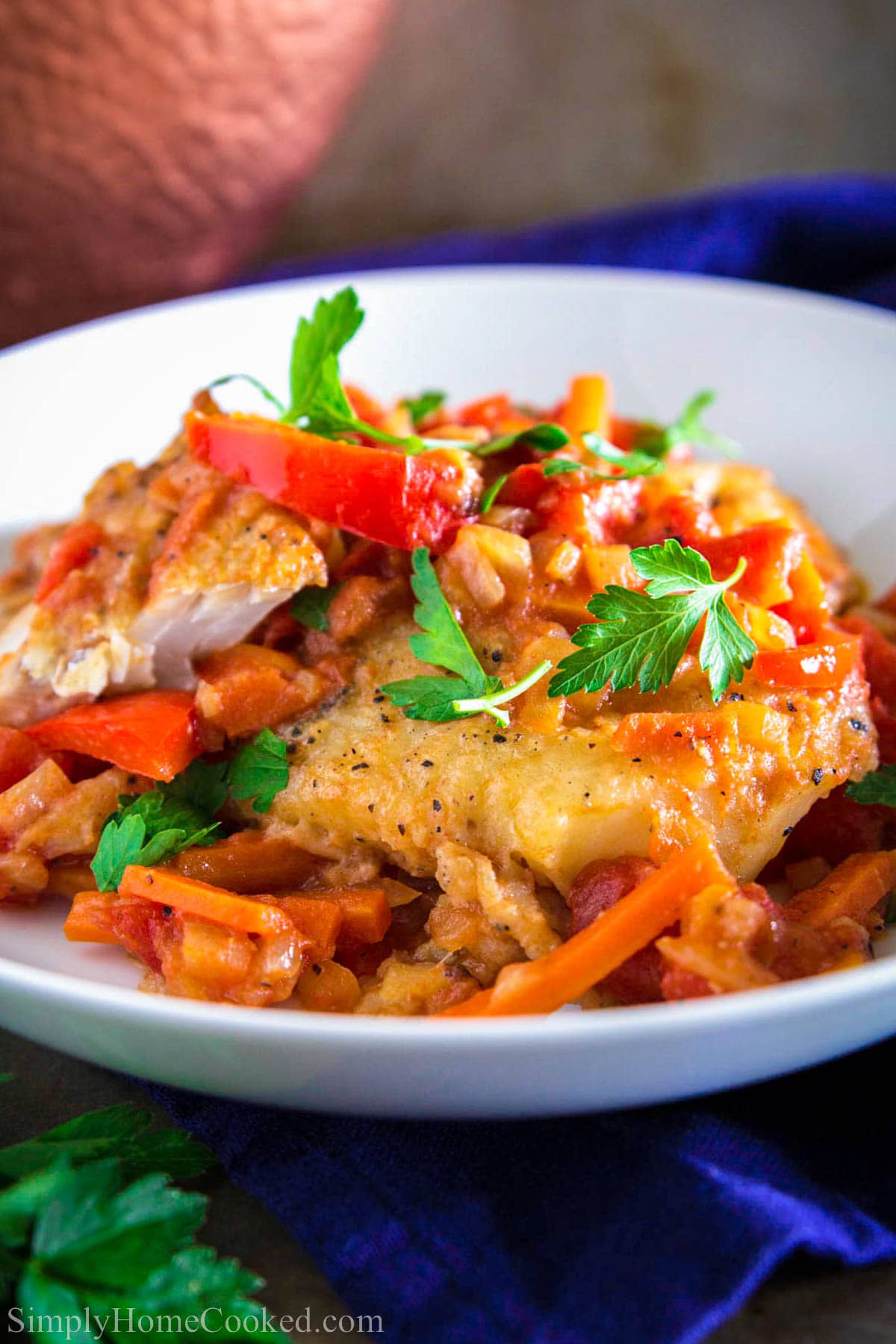 Pan Fried Cod with Sauteed Vegetables topped with parsley on a white plate.