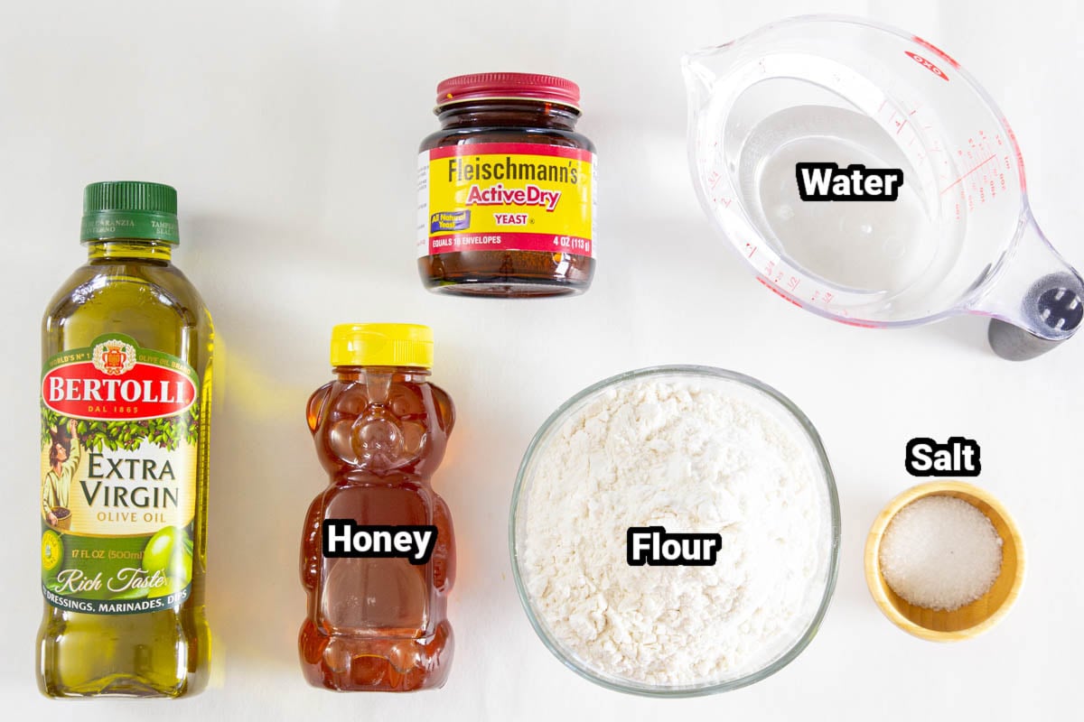 Ingredients for Homemade Pizza Dough: yeast, water, flour, salt, honey, and olive oil.