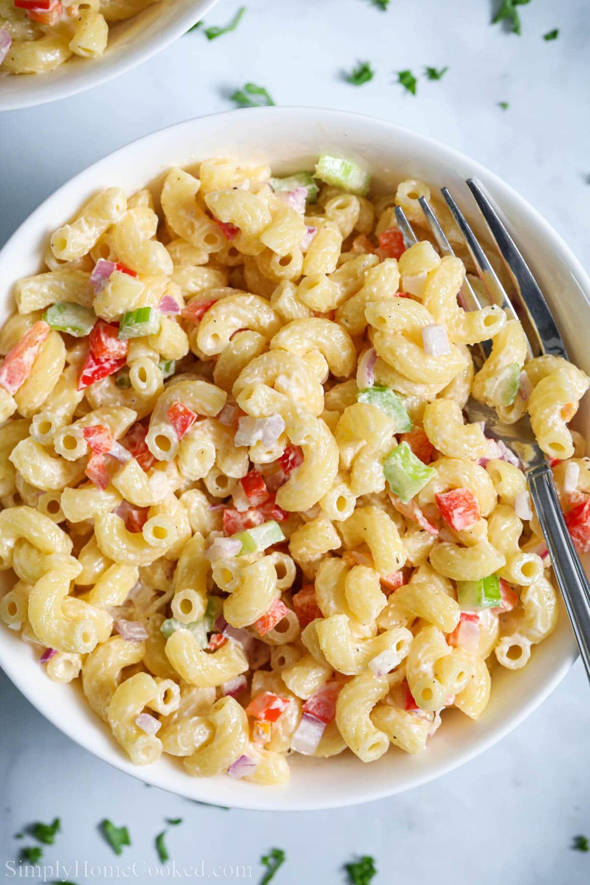 This Classic Creamy Pasta Salad is such a flavorful side dish. Creamy dressing and crispy diced vegetables mixed with elbow pasta make it oh so delicious. #creamypastasalad #classiccreamypastasalad #classicpastasalad #bestpastasalad Creamy Pasta Salad with diced vegetables and elbow macaroni in a bowl with a fork.
