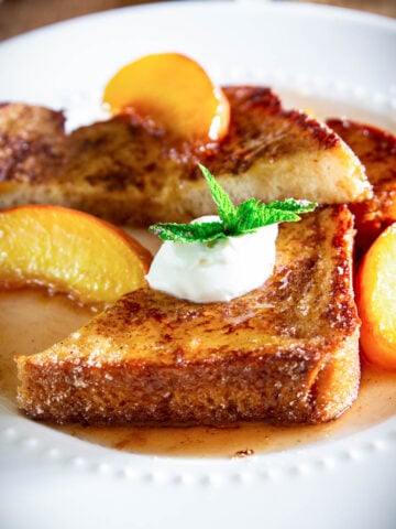 Peach French Toast topped with peach rum syrup, creme fraiche, and a spring of mint.